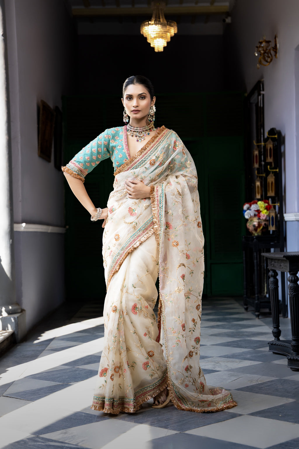 Ivory floral embroidered saree with teal blouse and ornate border