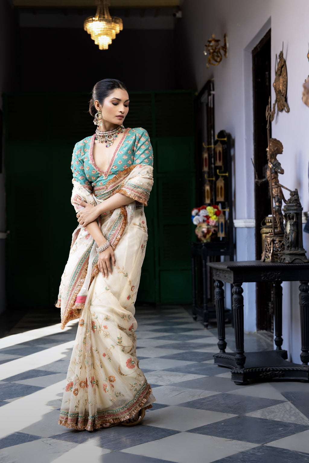 Ivory floral embroidered saree with teal blouse and ornate border